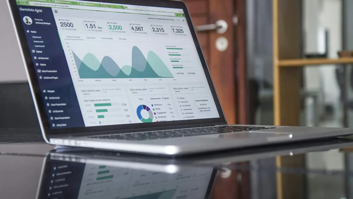 A laptop displaying an analytics dashboard with load time, active users and performance graphs